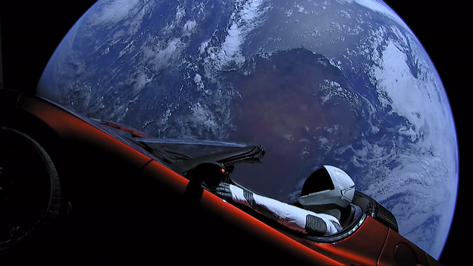 Cherry-red Tesla Roadster with Starman in the driver’s seat, Earth in the background