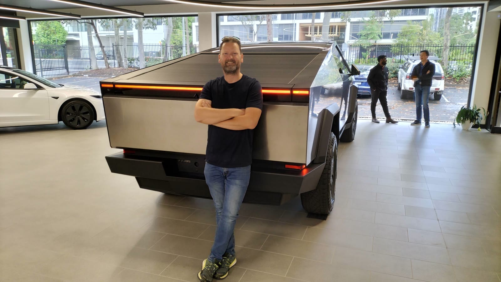 David standing behind a Cybertruck rear view in a Tesla showroom