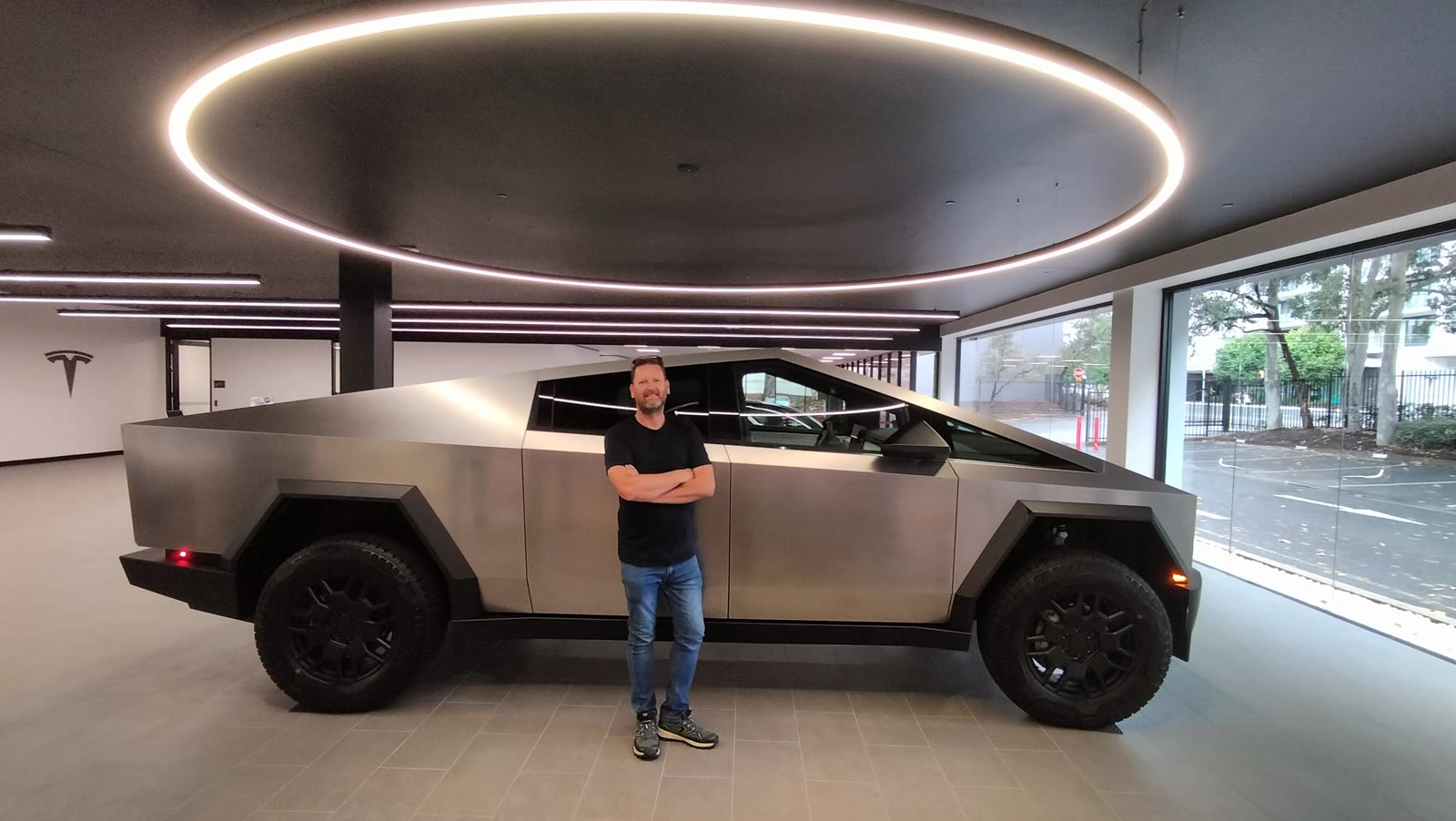 David standing in front of a Cybertruck side profile in a Tesla showroom